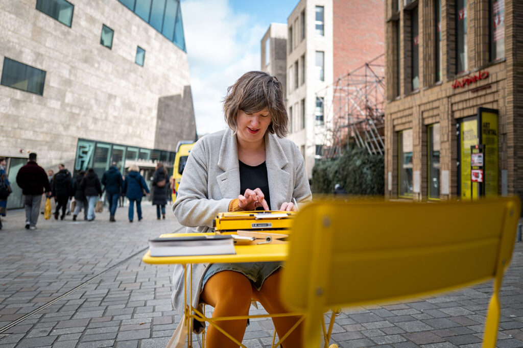Taalpracht met typmachine aan tafel op de Nieuwe Markt Groningen tijdens Nationale Complimentendag 2025