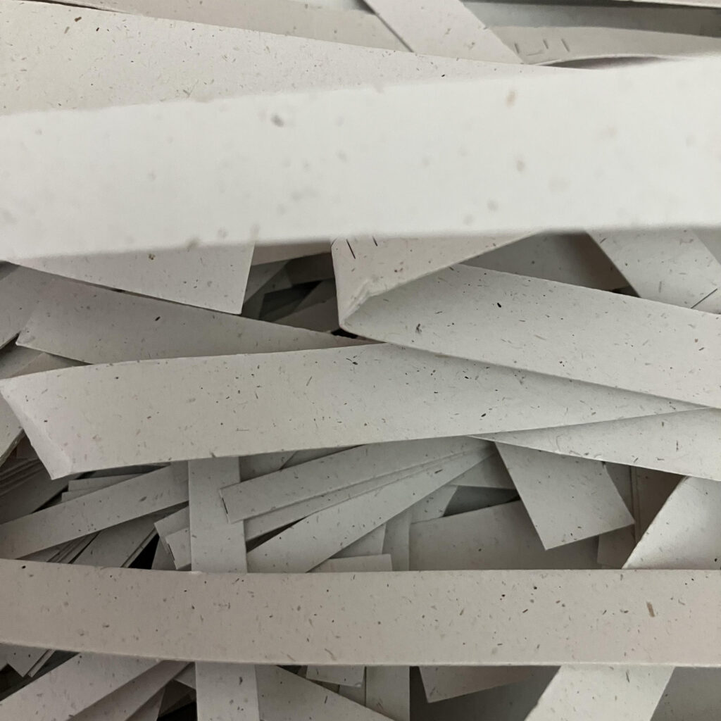 Stroken papier als snijafval van Taalpracht voor complimentenslinger