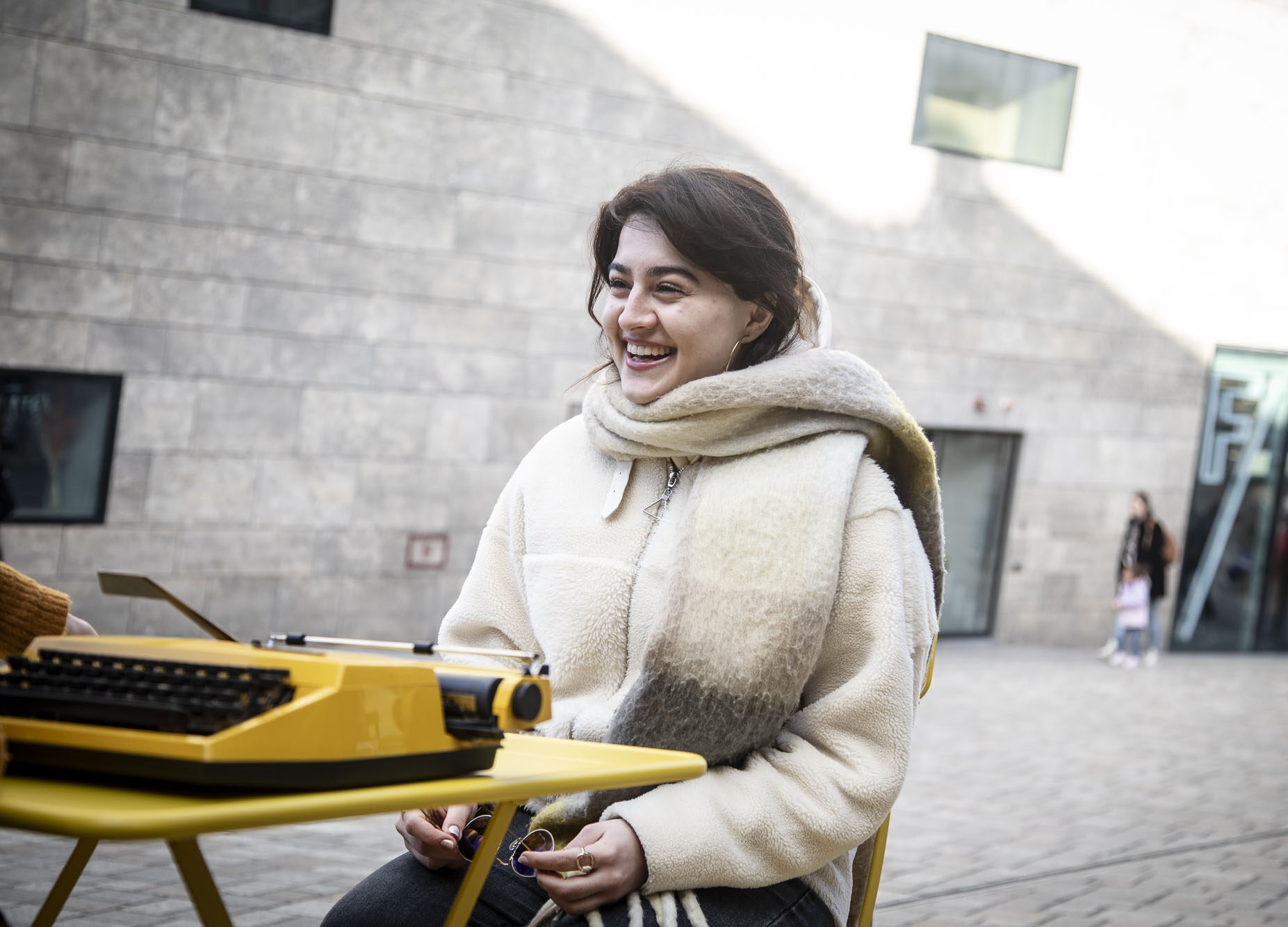 Vrouw met stralende lach aan tafel bij Taalpracht op Locatie